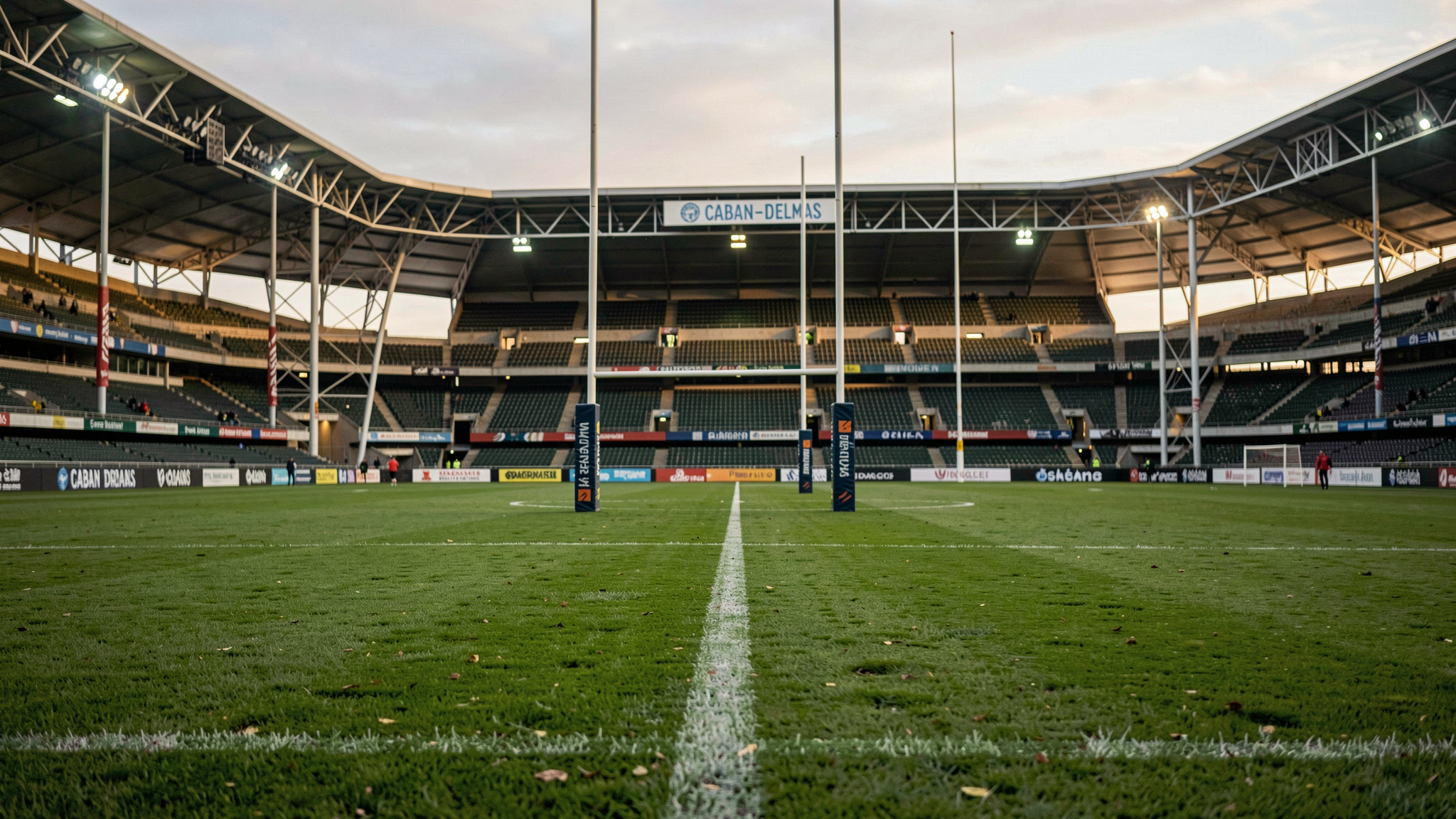 Bordeaux'daki Chaban-Delmas Stadyumu'nun yeşil çim sahası, akşam ışığında dikilmiş rugby direkleri, alçak açıdan geniş plan çekim